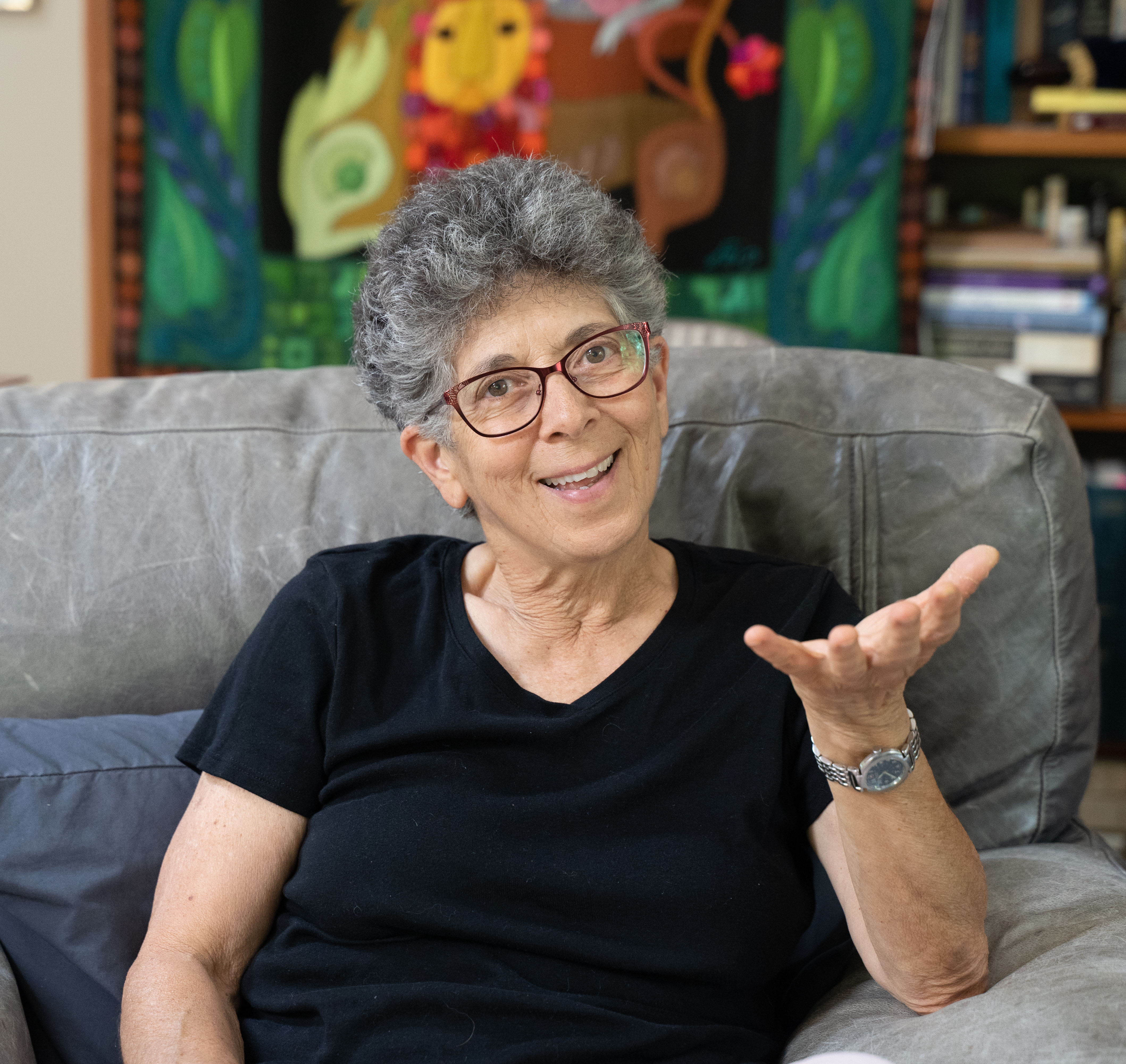 Suri in front of a tapestry